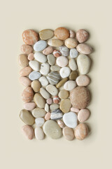 Creative arrangement of natural colored sea stones. Smooth round pebbles as square pattern on beige background. Minimal trend summer flat lay, top view still life composition with rocks