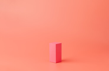 A small pink rectangle made of paper or cardboard. Geometric figure on a coral background.