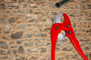 Plumber tools isolated. A red PVC pipe cutter for cutting plastic pipes and a piece of PE pressure...