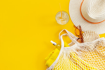 Summer background with straw hat and grid string bag. Beach flatlay
