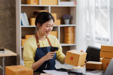 Startup SME small business entrepreneur of freelance Asian woman wearing apron using laptop and box to receive and review orders online to prepare to pack sell to customers, online sme business ideas. - obrazy, fototapety, plakaty