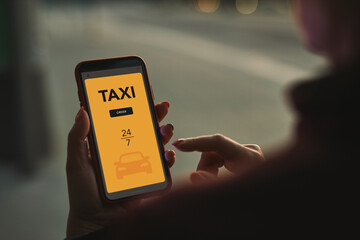 Woman ordering taxi online using mobile app on smart phone. Booking taxi using application online. Arranging taxi ride in downtown city street. Car sharing. Taxi service on mobile