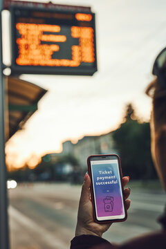 Woman Buying Ticket Online At Bus Stop Before Ride. Person Paying For Ticket Using Mobile Payment App. Using Technology On The Go. Order Confirmation On Mobile Screen