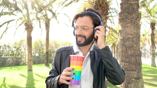 Homosexual man in headphones drinking beverage