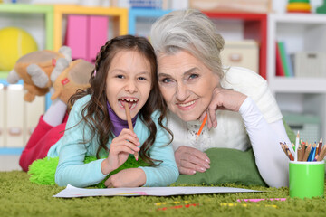 Naklejka premium Portrait of cute little girl drawing with grandmother