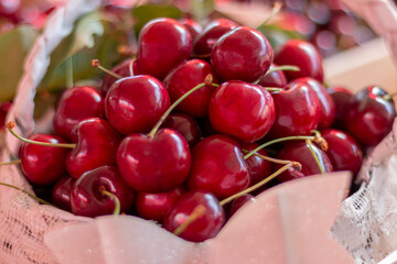 Red ripe fresh cherries in big wooden basket crate on farmers market stall.Close up