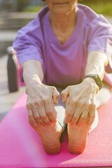 An old slender woman does yoga in the park