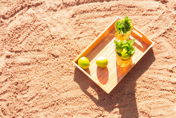 Two glasses of mojito cocktail on sand beach. Selective focus. Top view, copy space.