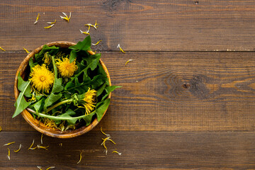 Meadow herbs and flowers. Yellow dandelions heads in wooden bowl