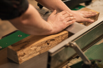 Close-up of carpenter, joiner worker hands pressing, pushing down, setting wood board on cutting...