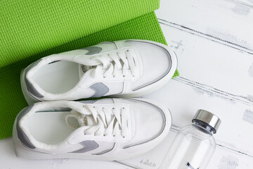sneakers, a water bottle on a green yoga mat. The concept of sport