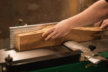 Close-up of carpenter working hands fixing wood bar, timber and work accurate with wood cutting machine in the workshop 