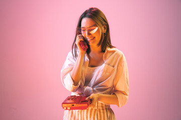 Studio shot of young pretty girl in summer fashion collection outfit posing isolated on pink background. Concept of emotions, facial expression, youth