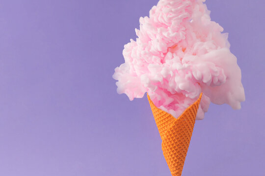 Orange ice cream cone with pastel pink color paint against purple background. Minimal abstract summer concept.  Surreal creative dessert food idea.