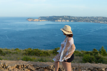 woman with hat contemplating the sea, tourist on the beach