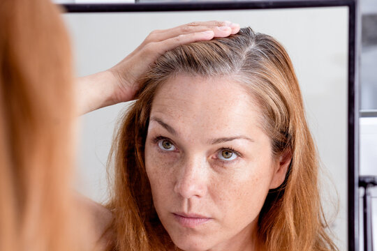 Gray Haired Caucasian Middle Aged Woman Looking At Grey Hair Head In Mirror Reflection