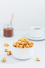 Sweet caramel popcorn in a ceramic bowl on a gray background