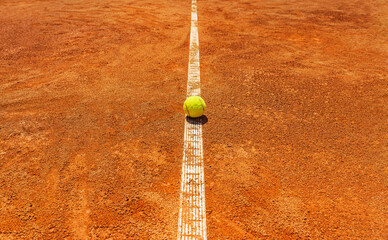  A yellow tennis ball lies on the clay court.