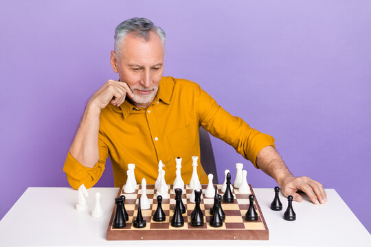 Photo of mature man look chessboard thoughtful concentrated idea isolated over violet color background