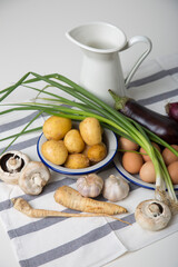 A set of essential products: milk, eggs, eggplant, garlic, potatoes, turnips and other vegetables. Rustic food on the table. White background.