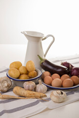 A set of essential products: milk, eggs, eggplant, garlic, potatoes, turnips and other vegetables. Rustic food on the table. White background.