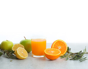 Glass of freshly squeezed juice, fresh apple, orange and lemon. Pistachio sprig on a gray stone table. White background. background for the restaurant menu.