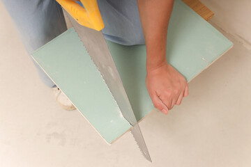 Female hands with a saw close-up sawing drywall