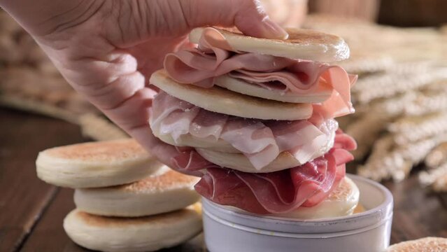 tigelle or crescentine homemade,an Italian food typical of the area of Modena.Thin round breads stuffed with prosciutto . Emilia-Romagna.Made from flour, water, salt, and yeast. Selective focus.4k