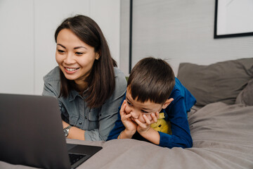 Young beautiful asian mother with her cute son watching cartoon