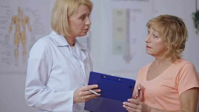 Professional physiatrist making prognosis for senior female patient, treatment