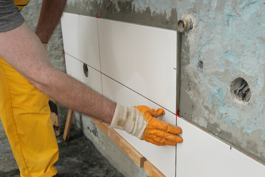 Worker placing ceramic tile to wall in a kitchen or bathroom