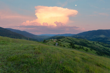 Beautiful summer mountain rural landscape. Small village and green pastures in the Carpathian mountains under beautiful summer cumulus clouds. Ukraine.