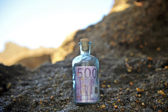 Bottiglia ritrovata sugli scogli del mare con dentro una banconota da cinquecento euro. 500 euro. Riciclaggio di denaro. Immagine per illustrare il trading di valuta.