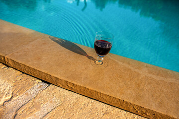 kieliszek z czerwonym winem na skraju basenu