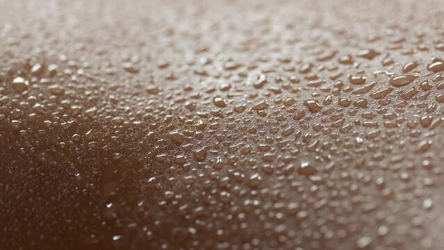 Macro shot of a lot of water drops on moving skin of young African American female model on black background | Skin texture shot for skin moisturizing concept