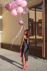 stylish african woman in black dress with balloons