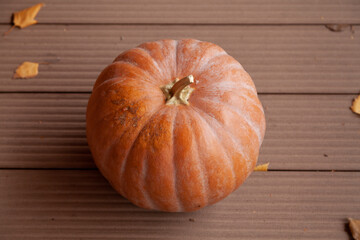 Round orange pumpkin and leaves on planks. View from above