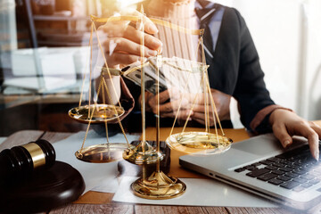 Justice and law concept.Male judge in a courtroom with the gavel, working with, computer and docking keyboard, eyeglasses, on table in morning light