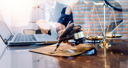 Justice and law concept.Male judge in a courtroom with the gavel, working with, computer and docking keyboard, eyeglasses, on table in morning light