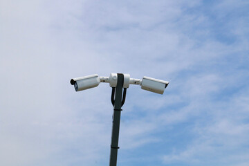 Two CCTV cameras on a pole point in opposite directions.