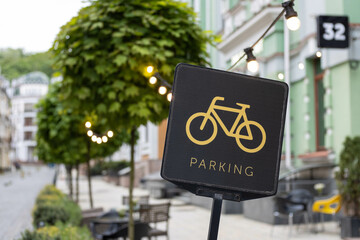 Obraz premium A black bicycle sign with a picture of yellow bike and text parking. Convenient infrastructure of big city streets. Parking area space for two-wheelers transport on the European street. Urban concept