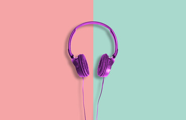 Computer headphones. Violet headphones on a green-red pastel background. The concept of listening to music, creating audio, music. Computer work, abstraction and minimalist style.