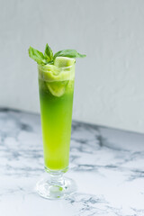 Green fresh summer cocktail with mint and cucumber on marble table for cafe menu