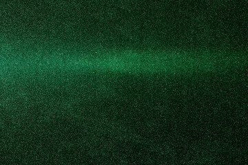 On a dark green rough background in fine grain, a green gradient beam of light