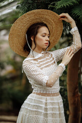 A young girl in a vintage dress in a tropical greenhouse.