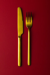 Gold cutlery on the red background.