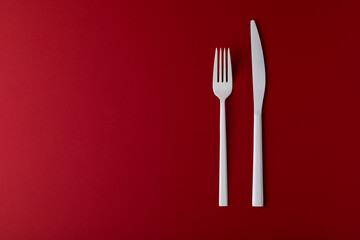 White cutlery on the red background.
