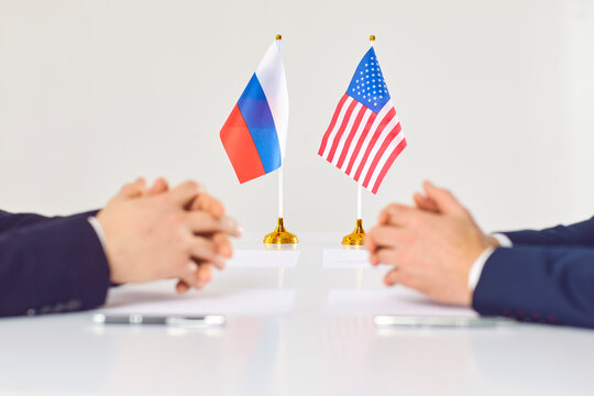 Closeup Of Russian And American Diplomats Sit At Table Discuss Relations. Politicians From USA And Russia Negotiate For Conflict Settlement. International Diplomacy. Stop War.