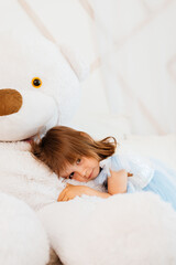 Girls playing on the bed with a big soft toy teddy bear