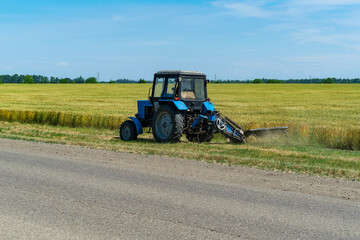 Road services landscaping around roads in tractor mows lawn grass with a mechanical mower mowing grass on the side of the asphalt road.A series of pictures.
